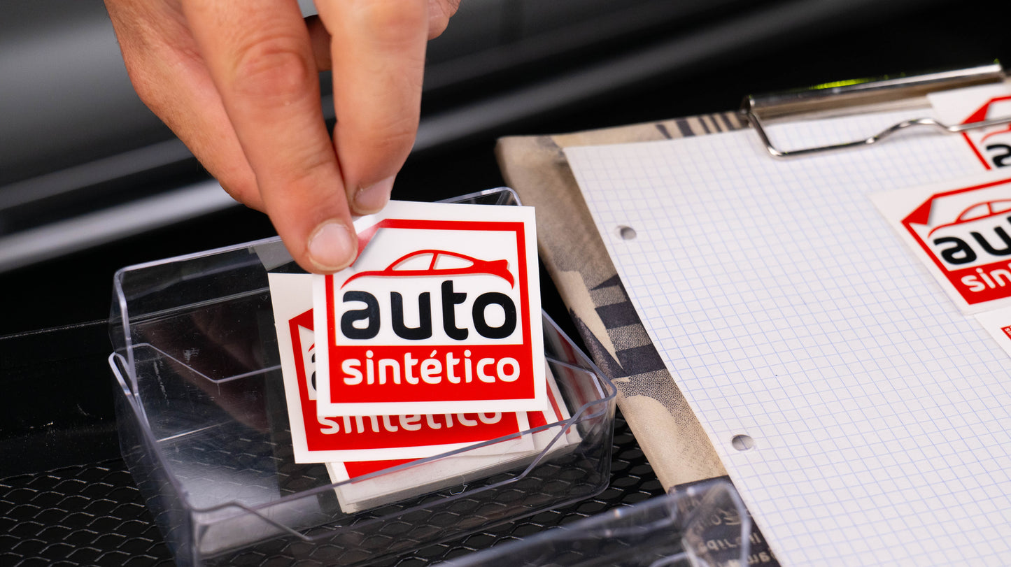 Persona organizando etiquetas de mantenimiento en una bandeja, con pegatinas de cambio de aceite de Auto Sintetico listas para su uso en talleres mecánicos